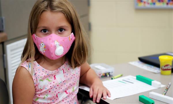 girl smiles while wearing mask